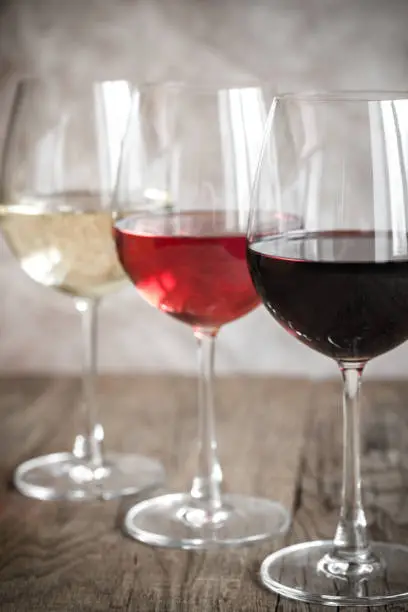 Glasses of red, rose and white wine on the wooden background