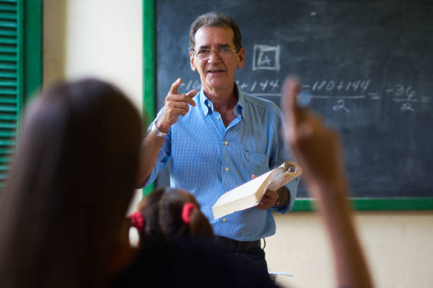 ragazza che alza la mano facendo domanda all'insegnante a scuola - professor teacher female blackboard foto e immagini stock