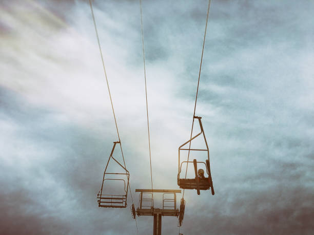 Young boy rides a chair lift at a ski resort during the beginning of a storm.
