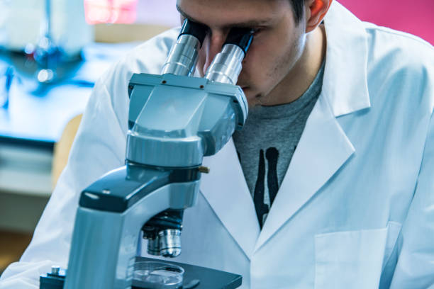 istock Male scientist looking through a microscope in laboratory, close up 641248594