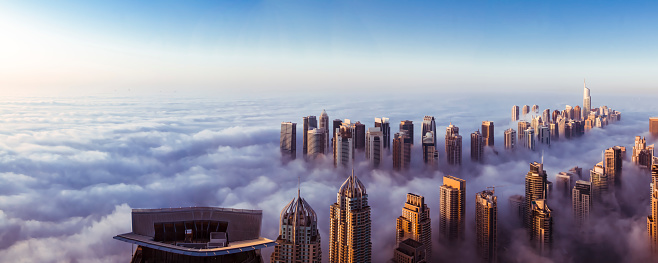 In this image Dubai Marina area is covered in fog and some buildings are sticking out above the clouds.