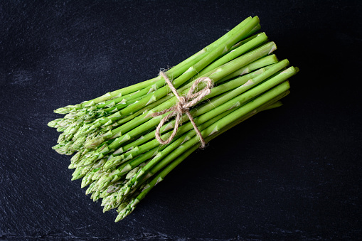 Green asparagus tied over slate background, top view, closeup