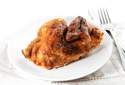 grilled half chicken served on a plate, napkin and silverware, background fades to white, selected focus, narrow depth of field