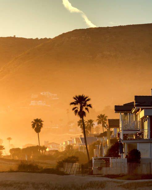 The Santa Monica mountains are the background for a hazy golden sunset on Malibu beach, California.