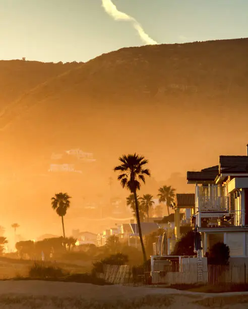 The Santa Monica mountains are the background for a hazy golden sunset on Malibu beach, California.