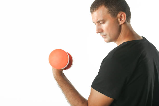 istock Young man exercising with orange dumbbells 641268998
