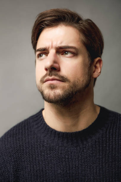istock thoughtful young man against gray background 641272214
