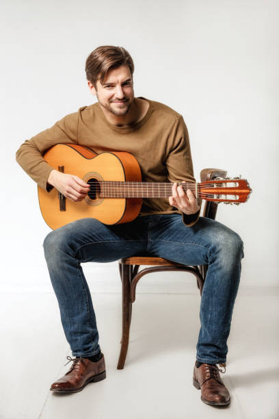 hombre sonriente tocando la guitarra - isolated on white studio shot guitar young men fotografías e imágenes de stock