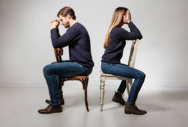 seitenansicht des depressiv paar sitzen rücken an rücken auf stühlen - relationship difficulties couple anger communication breakdown stock-fotos und bilder