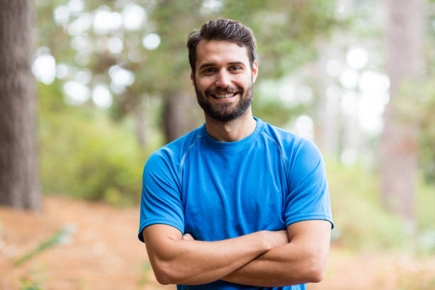 istock Smiling man standing in forest with arms crossed 641273474