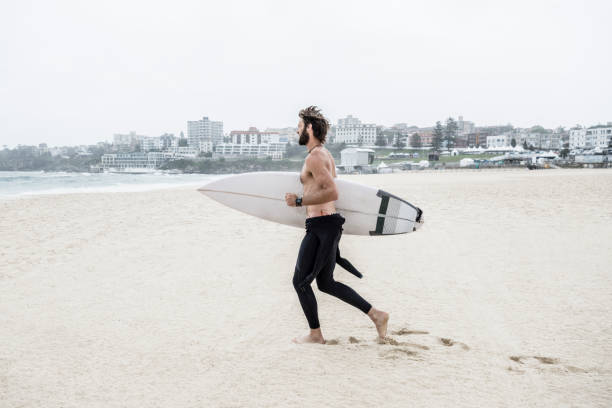 istock Male surfer in his 30s running on beach with surfboard 641274806