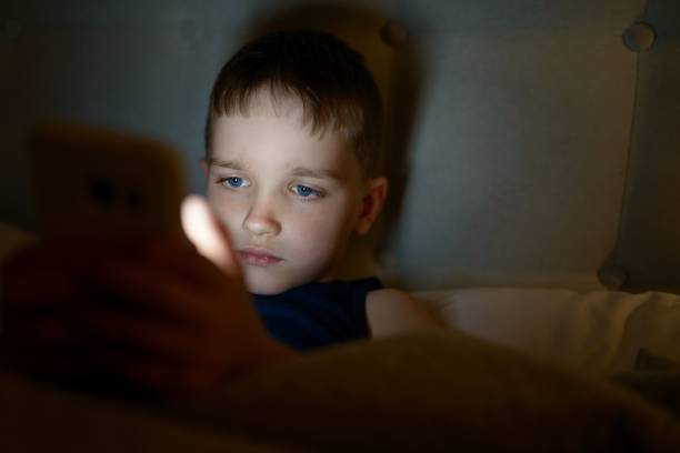 istock 7 years old child boy using smartphone at night 641275322