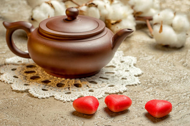 Teapot and three marzipan in the shape of hearts, a festive tea party Valentine's Day.