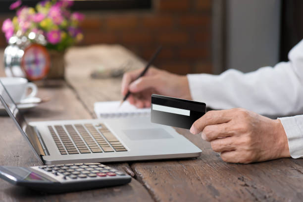 man hand holding credit card and writing a note. - bar code computer keyboard retail computer imagens e fotografias de stock