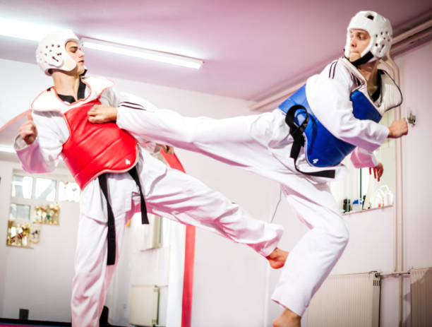 dos luchadores de taekwondo competirán y practican patadas altas con equipo de protección - taekwondo fotografías e imágenes de stock