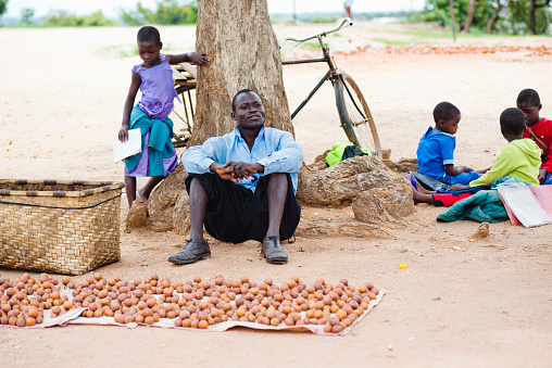 A man selling wild loquat outside a primary school in Malawi. In Malawi, these fruits are called Masuku; and Oilumbula, Mumbola, Nt'junku or Matu in other African languages.