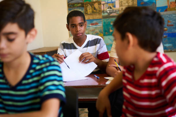 amici che barano durante il test a scuola e studenti che studiano - child caribbean black latin american and hispanic ethnicity foto e immagini stock