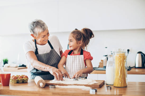 Making cookies with grandma Senior woman and a small girl preparing cookies grandmother stock pictures, royalty-free photos & images