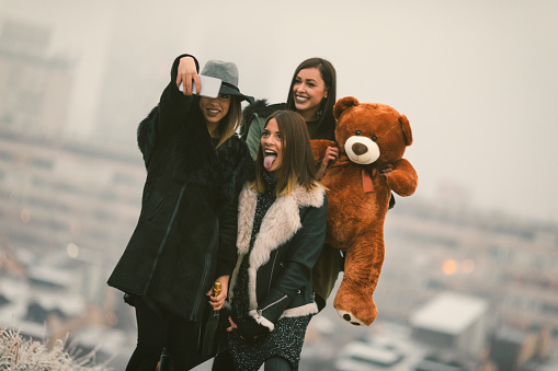 Happy Young Women making selfie outdoors on the top of the hill with city in background