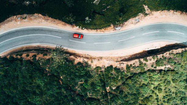 Aerial view on red car on the road near tea plantation Aerial view on  red car on the road near green tea plantation in mountains in Sri Lanka thoroughfare stock pictures, royalty-free photos & images