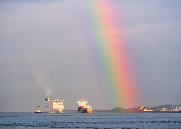 Ships entering harbor under rainbow stock photo