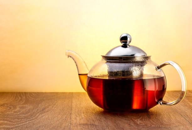 istock Glass teapot with tea on wooden surface on yellow background 641300978
