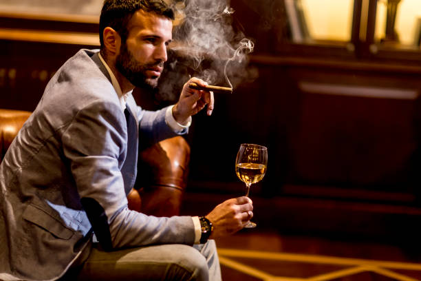 Young man tasting white wine Young man tasting white wine and smoking cigar man cigar stock pictures, royalty-free photos & images