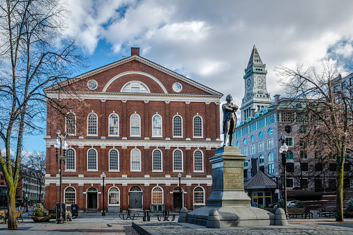 Boston, MA, USA - November 23, 2022: Tourists and locals strolling on the Dock square near the Samuel Adams statue at Faneuil Hall in Boston, MA. Samuel Adams was an American statesman, political philosopher, and one of the founding fathers of the United States.