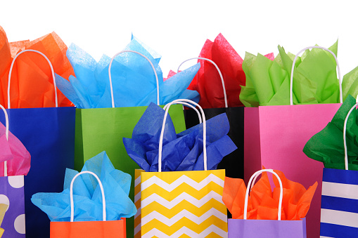 Brightly colored gift bags with color tissue paper on a white background.