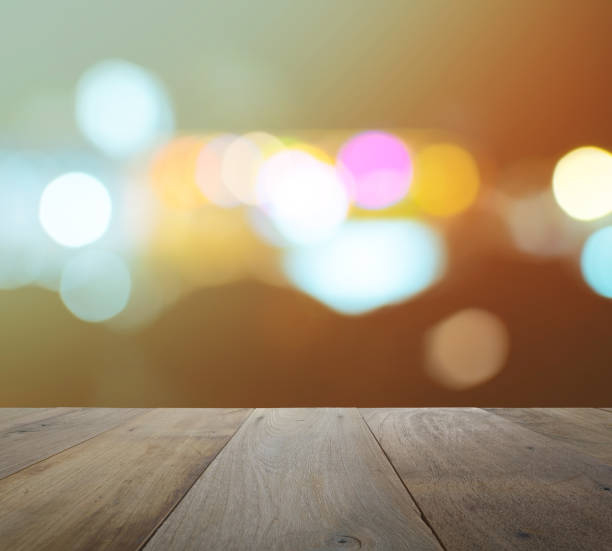 istock wood table top on abstract background with bokeh defocused lights and shadow from cityscape at night, vintage or retro color tone 641316894