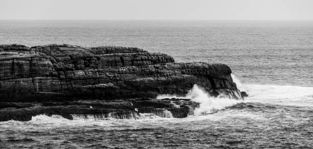istock Ocean waves breaking on rugged coastal cliffs. Black and white landscape 641320040