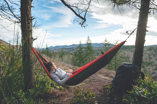 Woman relaxing in hammock by herself deep in forest.