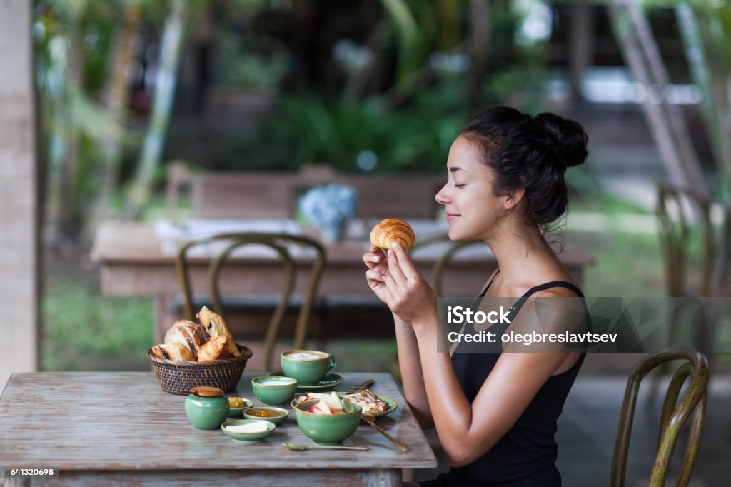 Young woman enjoying breakfast and holding croissant in hand. Morning good mood Young woman having breakfast and holding croissant in hand. Morning good mood Butter Stock Photo