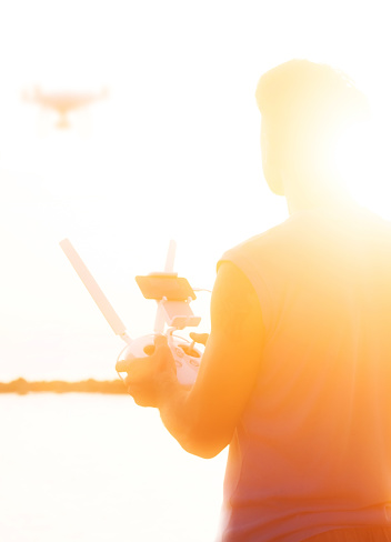 Silhouette of man operating drone quadcopter Dji Phantom 4 at sunset in Koh Phangan island