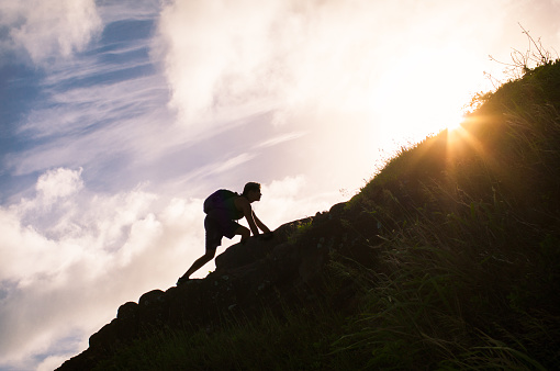 Young man climbing up a mountain.