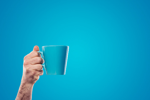 istock Hand holding blue cup on blue background 641330692