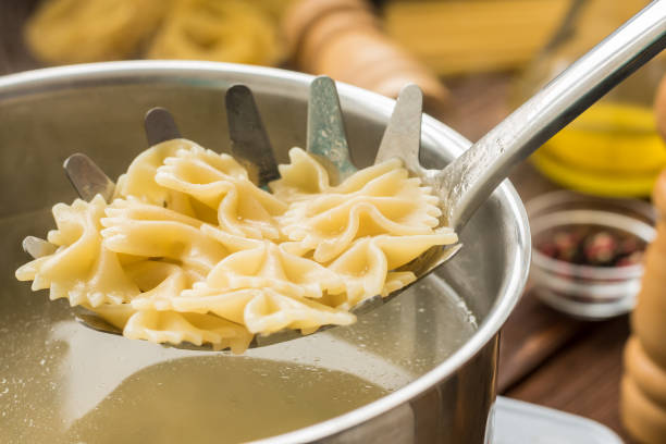 Boiled farfalle on the pasta spoon Boiled hot farfalle on the pasta spoon boiled water stock pictures, royalty-free photos & images