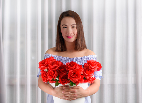 Woman holding a bouquet of red roses with a translucent cloth background.