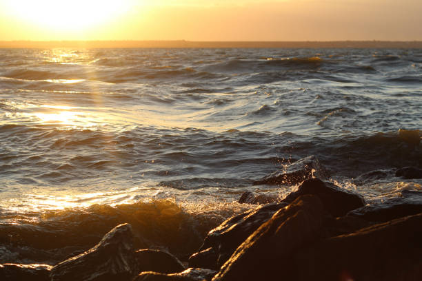 istock Waves beat crash rocks on lake shore storm at sunest 641342602
