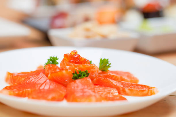 Japanese food salmon sashimi slices on a white plate, isolated white background.