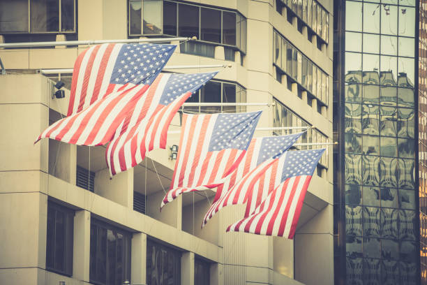 istock Side view of windy American flags on flagpoles on building. 641343674