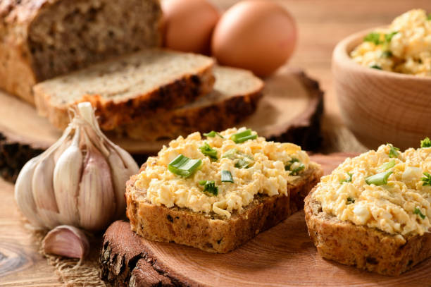 istock Whole wheat sandwiches with egg and cheese spread on wooden stump. 641346650