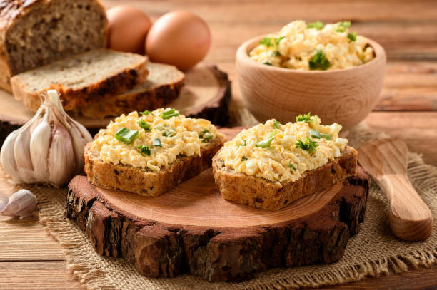 istock Whole wheat sandwiches with egg and cheese spread on wooden stump. 641346676