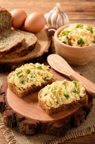 istock Whole wheat sandwiches with egg and cheese spread on wooden stump. 641346694