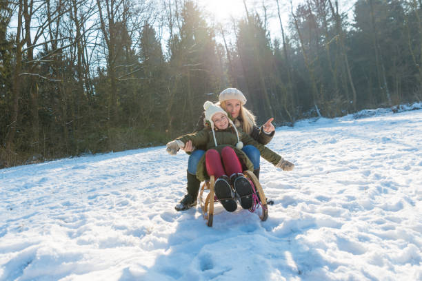 istock Mother and daughter haveing fun on sleds 641355062
