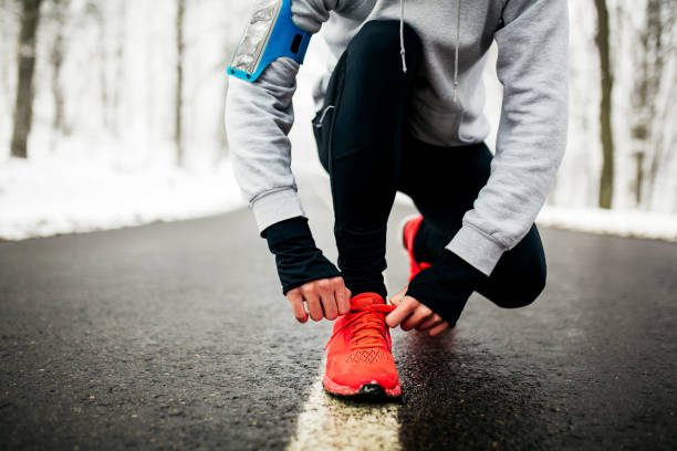 若いランナーの彼の靴ひもを結ぶ - running jogging men shoe ストックフォトと画像