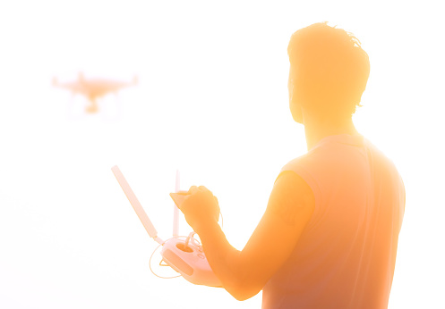 Silhouette of man operating drone quadcopter Dji Phantom 4 at sunset in Koh Phangan island