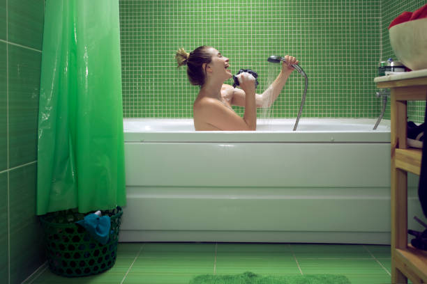 side view of woman inside bathroom singing and feeling happy, enjoying relaxing moment.green tile and shower curtain.