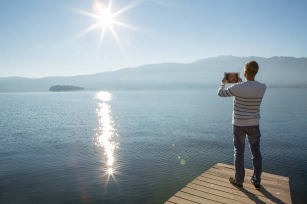 istock Young man relaxing on lake pier with digital tablet 641375578