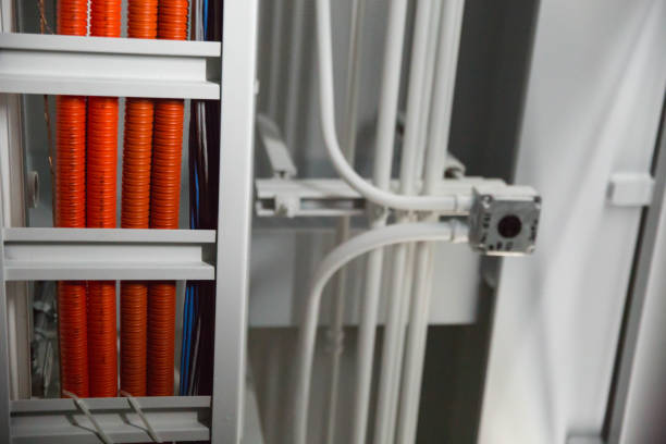 Orange cable housings and pipes run on ceiling during the day.